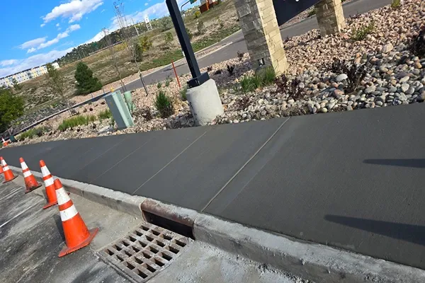 Broom-finished concrete sidewalk beside a storm drain in Colorado Springs