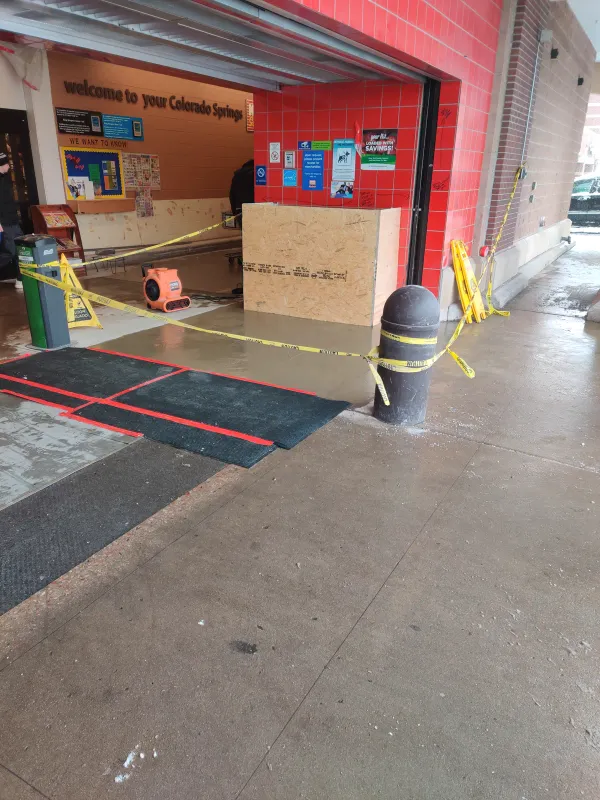 Fresh concrete patch back at a grocery store entrance in Colorado Springs, cordoned off with caution tape