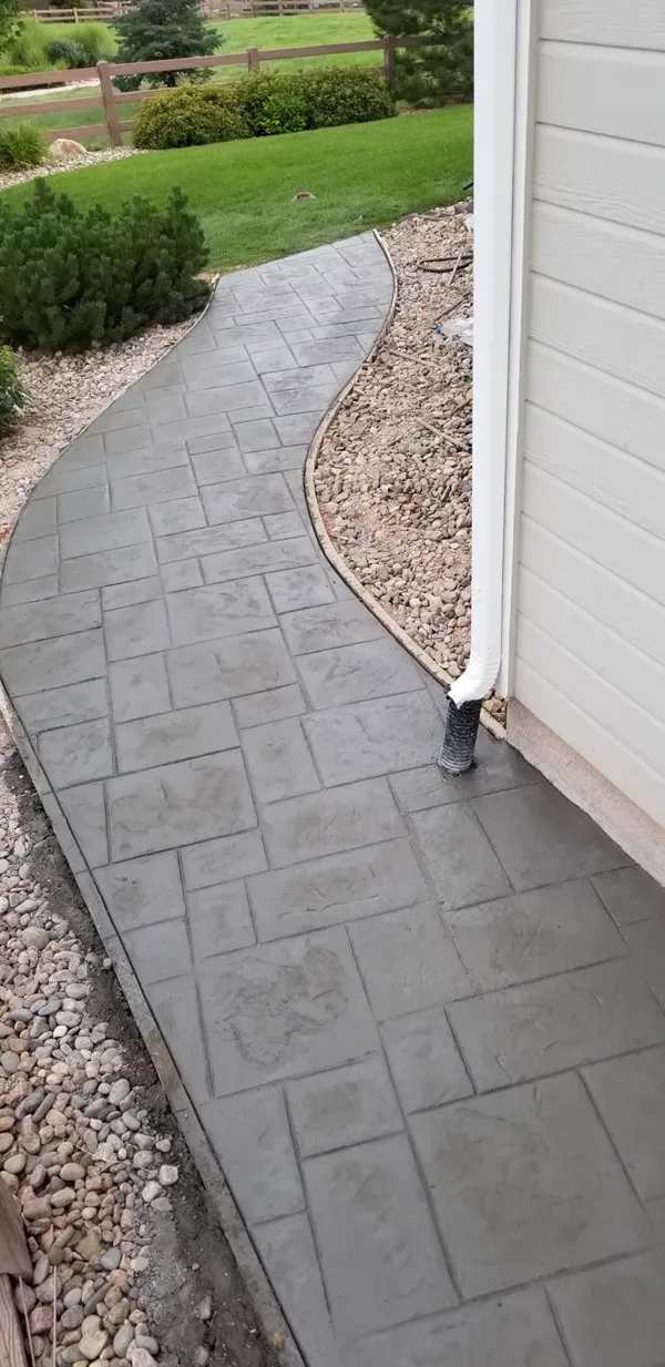 Curved stamped ashlar concrete walkway along a home in Colorado Springs