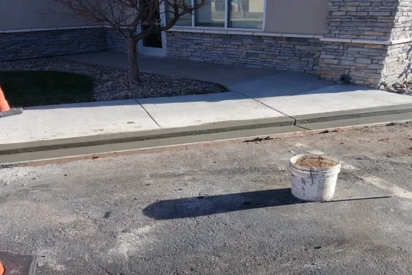 New concrete curb and sidewalk along a stone building in Colorado Springs