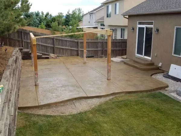 Tan stamped concrete backyard patio with a curved edge in Colorado Springs