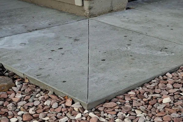 Concrete sidewalk panels with a control joint beside landscape rock in Colorado Springs