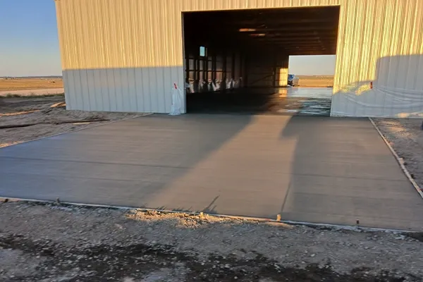 Newly poured concrete apron slab at a steel building entrance near Colorado Springs